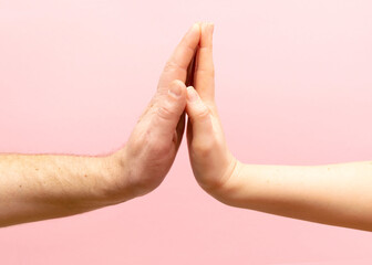 young woman and man holding hands together on pink background.