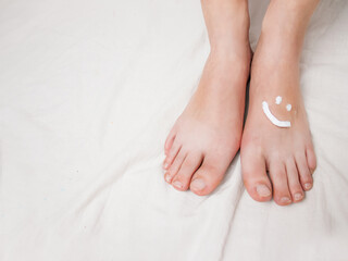 foot cream on female feet cream in the form of a smiley, close-up, on a white background, foot...
