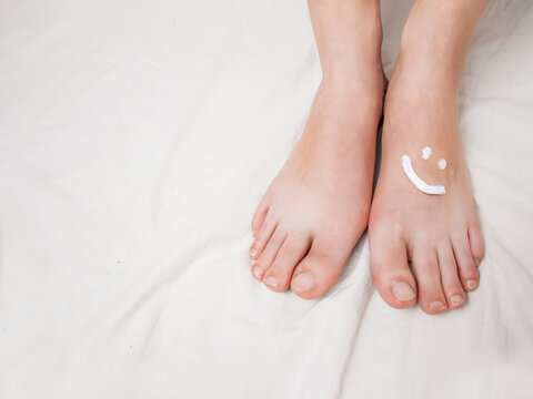 foot cream on female feet cream in the form of a smiley, close-up, on a white background, foot care, pedicure