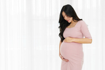 happy pregnant woman stroking belly on window background - obrazy, fototapety, plakaty