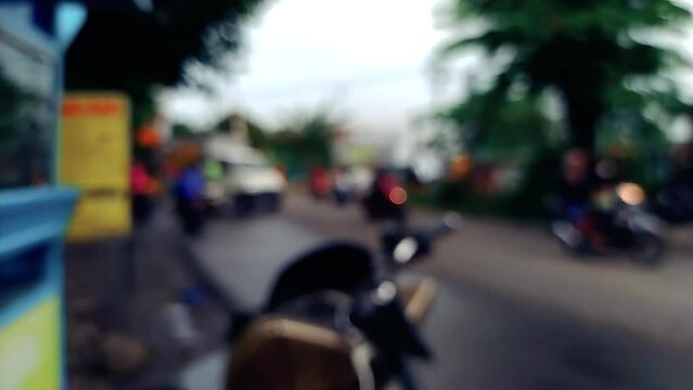 slow motion slomo of defocused bokeh blur footage of asian indonesian street at afternoon after rain with bike and car passing by