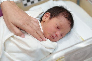 Fototapeta na wymiar hand of mother putting newborn baby to sleep in the infant bassinet basket at hospital