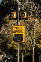 Yellow digital sign measuring traffic speed. The sign says Your Speed  and shows Slow Down in...
