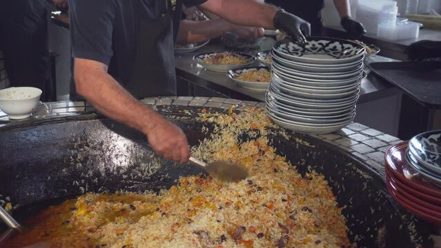 Cookers are putting plov (pilaf) on plates, Tashkent, Uzbekistan