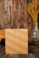 mockup square kraft paper card on wood table and decor with wicker decoration items.