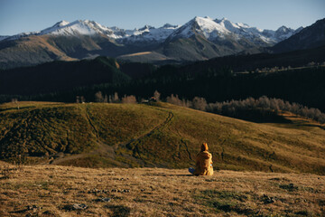 A woman standing in the fall sits in the distance travels to the mountains in nature hiking and...