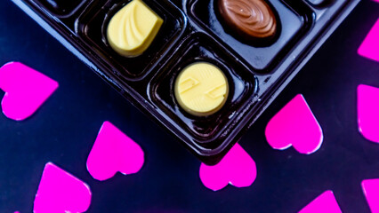 delicious chocolate surrounded by pink hearts on black background