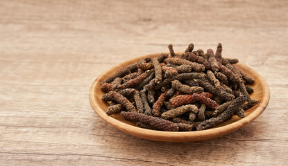 long pepper or piper longum in wood plate on wood table background. heap of long pepper or piper longum. long pepper, piper longum                          
