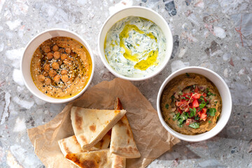 Pita with assorted traditional greek dips, tzatziki, vegetable caviar, hummus over light background.