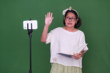 Woman standing and waving her hand in front of her gadget during an online class