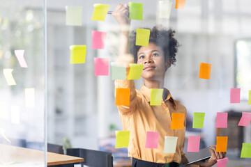 Young Serious african american Creative team use post it notes to share idea sticky note on glass...