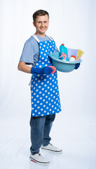 a man in a blue apron, rubber gloves, an orange t-shirt, jeans and white sneakers holds a basin of...