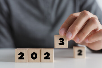 Man hand putting wooden cube block to change 2022 year to 2023 year. start to year 2023. happy new years concept.