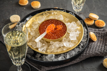 Orange Keta Lachs Kaviar in Dose auf Eis in Glas Schale mit Perlmutt Löffel, Sekt Champagner und...