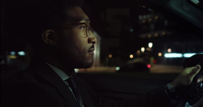 Portrait of a Handsome Black Man in a Suit Driving a Fancy Car at Night and Focused on the Road. Successful African American Businessman Driving Back Safely from Work, Thinking about Business Plans 