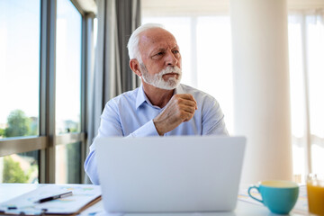 Fototapeta premium Financial advisor businessman using his laptop and doing some paperwork while sitting at desk and working.