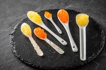 Kaviar von orange Keta Lachs und gelb Saibling mit Auswahl von Löffel aus Perlmutt, Plastik,...