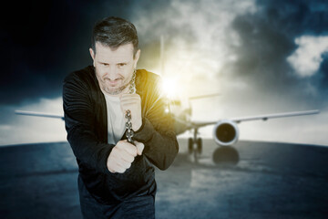Caucasian man pulling an airplane with a chain