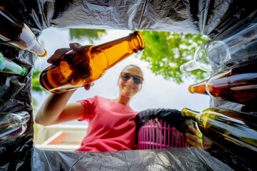 A young beautiful girl throws sorted garbage into special bins