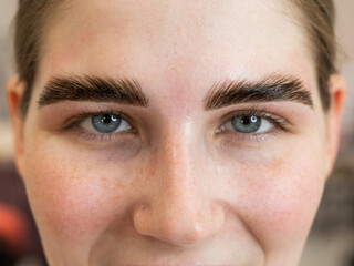 Close-up portrait of a woman after the procedure of correction and lamination of eyebrows. 