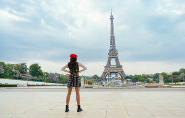 Beautiful young woman visiting paris and the eiffel tower. Parisian girl with red hat and...