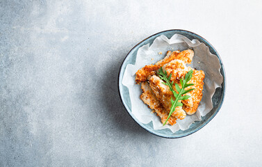Homemade chicken strips in a ceramic bowl, top view, copy space