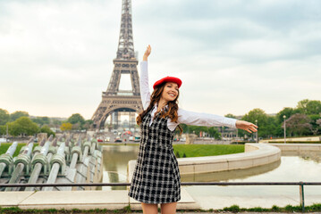 Beautiful young woman visiting paris and the eiffel tower. Parisian girl with red hat and fashionable clothes having fun in the city center and landmarks area