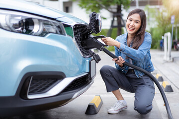 Beautiful Asian woman connecting a DC CCS2 EV charging connector to a vehicle, woman preparing an...