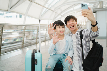 Father and son using smartphone to take a photo or video call.