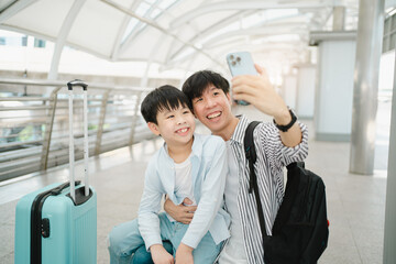 Father and son using smartphone to take a photo or video call.