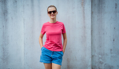 Obraz na płótnie Canvas Female model wearing pink blank t-shirt on the background of an gray wall.