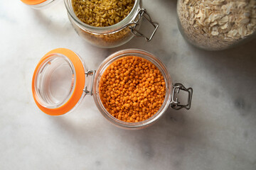 glass jar with red lentils on white table top view. jars of lentils, bulgur and oatmeal.