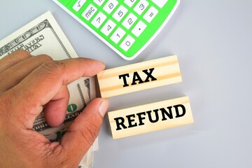 calculator, paper money and a hand holding a stick with the word tax refund