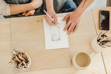 A woman draws a sketch of a ceramic vase