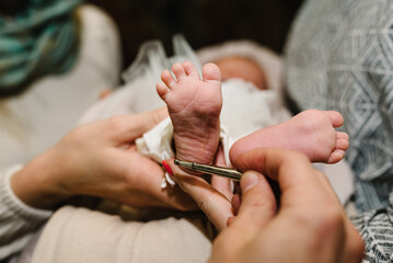 Baptism ceremony of a baby. Close up of tiny baby feet, the sacrament of baptism. The godfather...