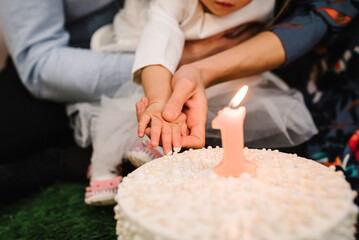 Birthday cake for 1 year. The child eats a holiday cake.  The cake is decorated with candle and decor for the girl. Delicious reception at a birthday party. Trendy cake.