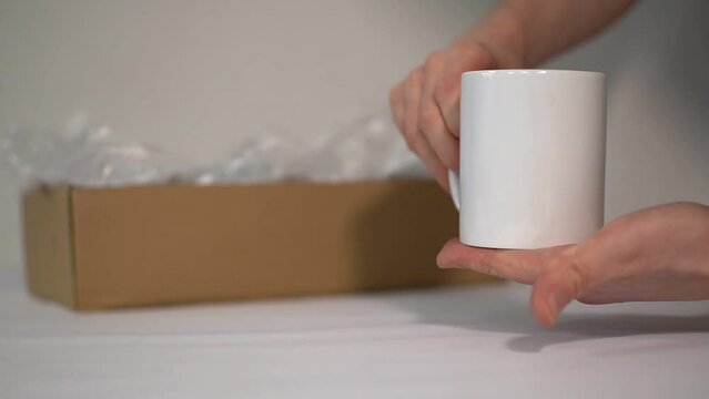 a man shows a close-up of a white ceramic mug on which you can apply an logo or an advertisement. High quality Full HD video recording
