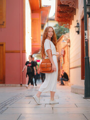 Obraz premium Happy woman tourist on background of blooming street of Antalya. female tourist traveler discover interesting places and popular attractions and walks in the old city Kalechi of Antalya, Turkey.