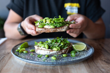Avocado toast with poached egg on a wooden table. edamame, lime, herbs, breakfast concept, food styling