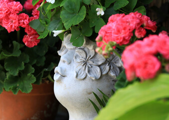 Romantic ornament among rose pelargonium on a shelf in the english cottage garden.