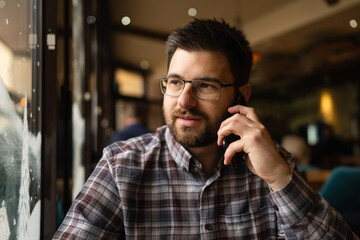 Bearded Man sitting alone at cafe or restaurant use smart phone