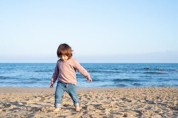 Cheerful female toddler running at the beach.