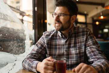 Bearded Man sitting alone at cafe or restaurant with glass cup of tea