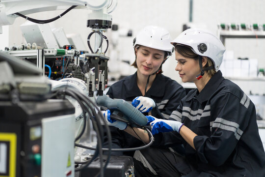 Two female engineers control autonomous mobile robot or AMR in the manufacturing automation and robotics academy room. Group of female engineers training or maintenance AI robot