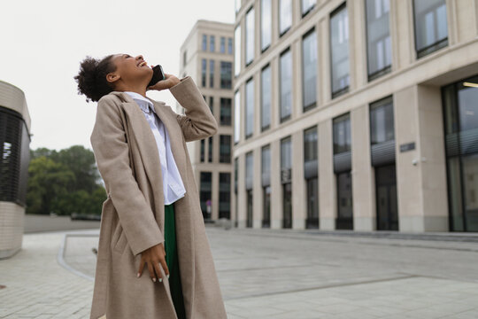 Young African American Woman Talking On Mobile Phone Outside With Her Head Thrown Back And Laughing