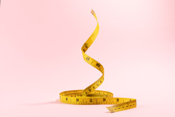 Yellow measuring tape on pink background