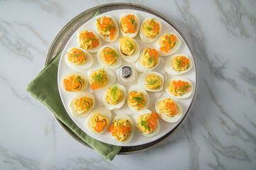 Gefüllte teuflische russische Eier mit Dill und orange Keta Lachs und gelb Saibling Kaviar auf Eierteller, Serviette grün, Silber Teller und Marmor Hintergrund hell