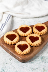 Heart shaped cookies on wooden serving board on gray background. Cookies with marmalade filling in the middle. Bakery desserts. close up
