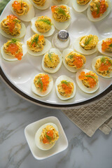 Gefüllte teuflische russische Eier mit Dill und orange Keta Lachs und gelb Saibling Kaviar auf Eierteller, Serviette grün, Silber Teller und Marmor Hintergrund hell