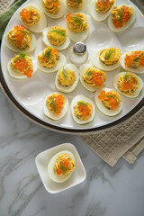 Gefüllte teuflische russische Eier mit Dill und orange Keta Lachs und gelb Saibling Kaviar auf Eierteller, Serviette grün, Silber Teller und Marmor Hintergrund hell